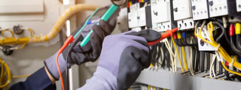 Electrician engineer tests electrical installations and wires on relay protection system. Adjustment of scheme of automation and control of electrical equipment.